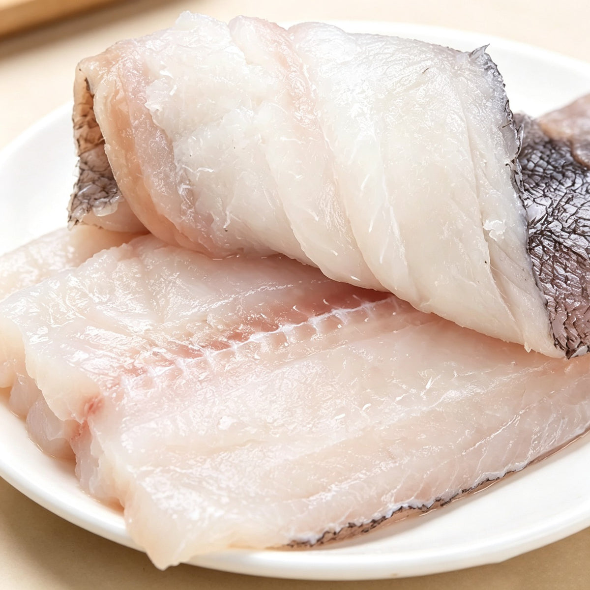 Close-up of plump white sole fillets on a white plate