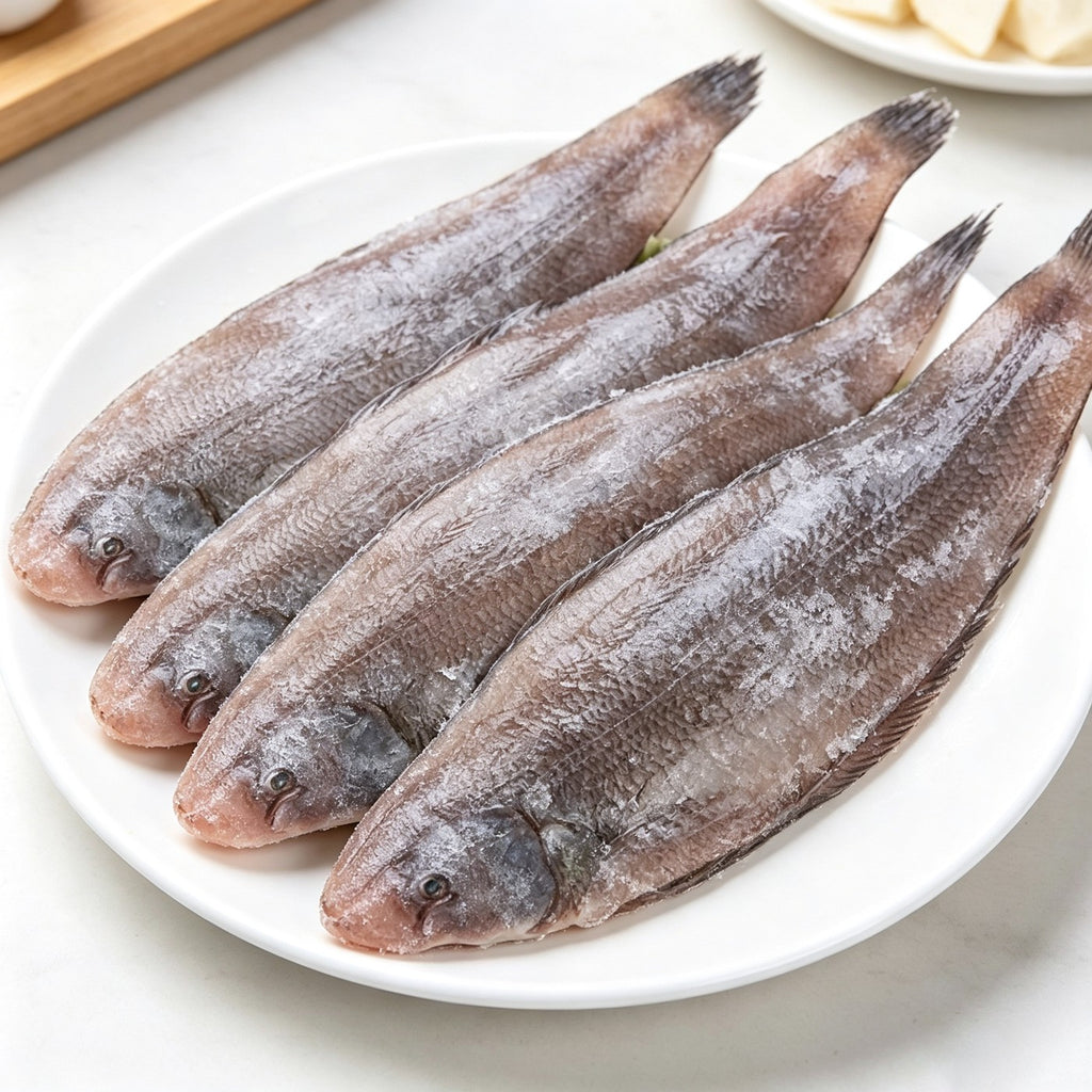 Several whole sole fish laid out on a white plate