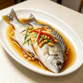 Whole bream steamed on a plate with chilli and spring onion